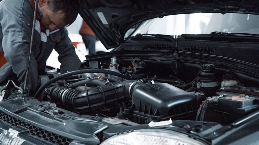 A mechanic inspecting an open engine bay.