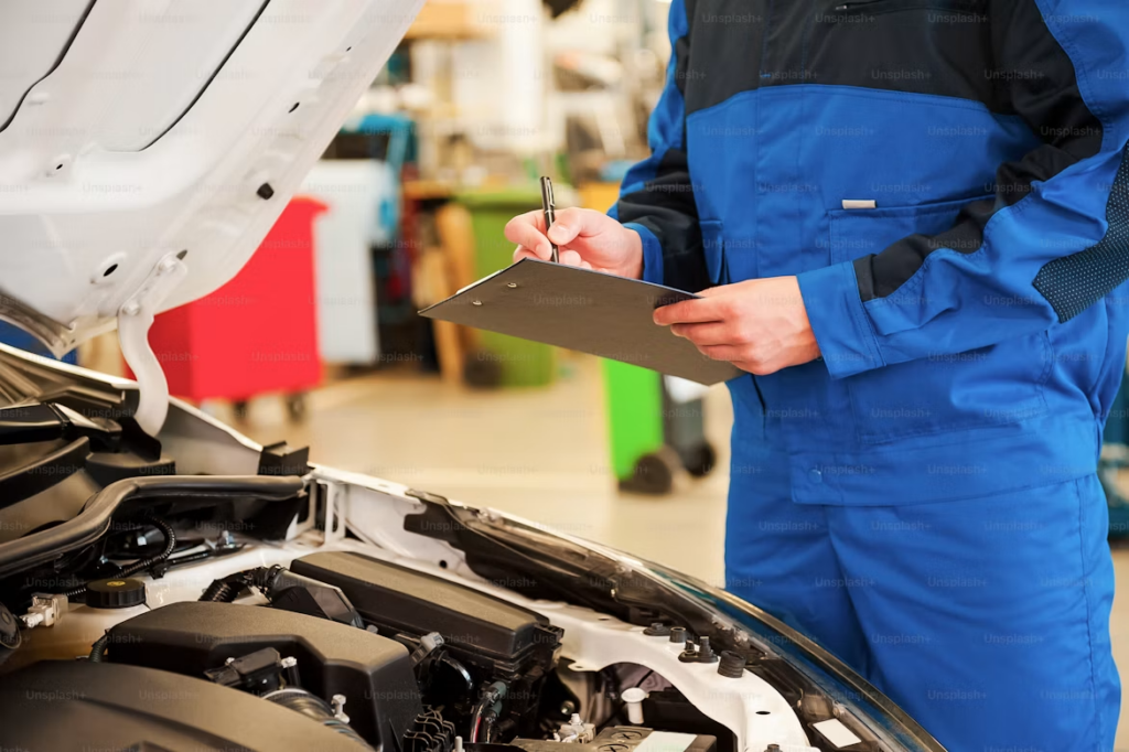 A mechanic taking notes beside an open bonnet.