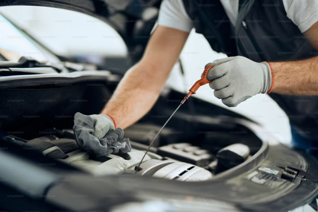 What Does Car Service Include: Mechanic checking engine oil.