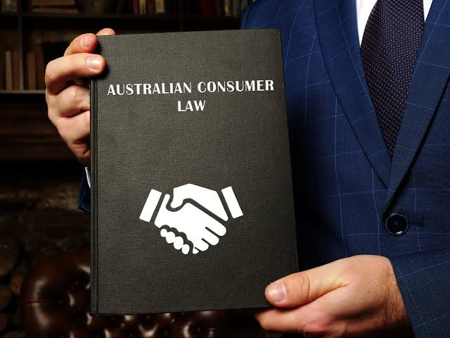 Log book service: man in suit holding Australian Consumer Law book.