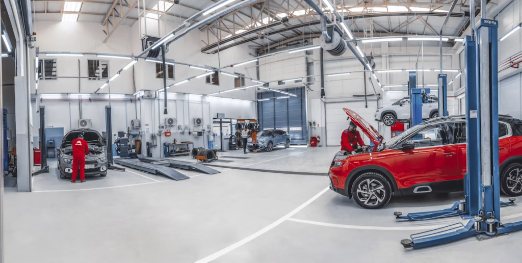Workshop with mechanics servicing several cars on hydraulic lifts.
