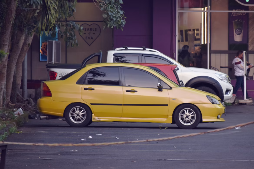 yellow modified sedan parked outside shops