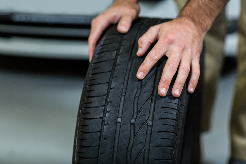 Mechanic checking tyre tread and sidewalls for wear, a common reason a car fails inspection
