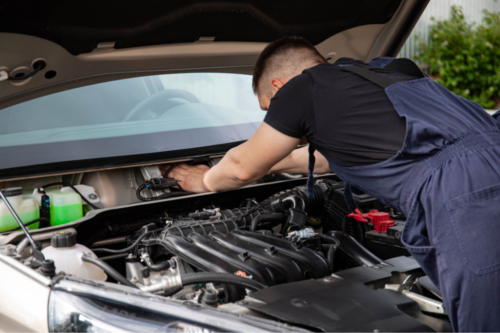 Car maintenance charges: mechanic inspecting engine bay.