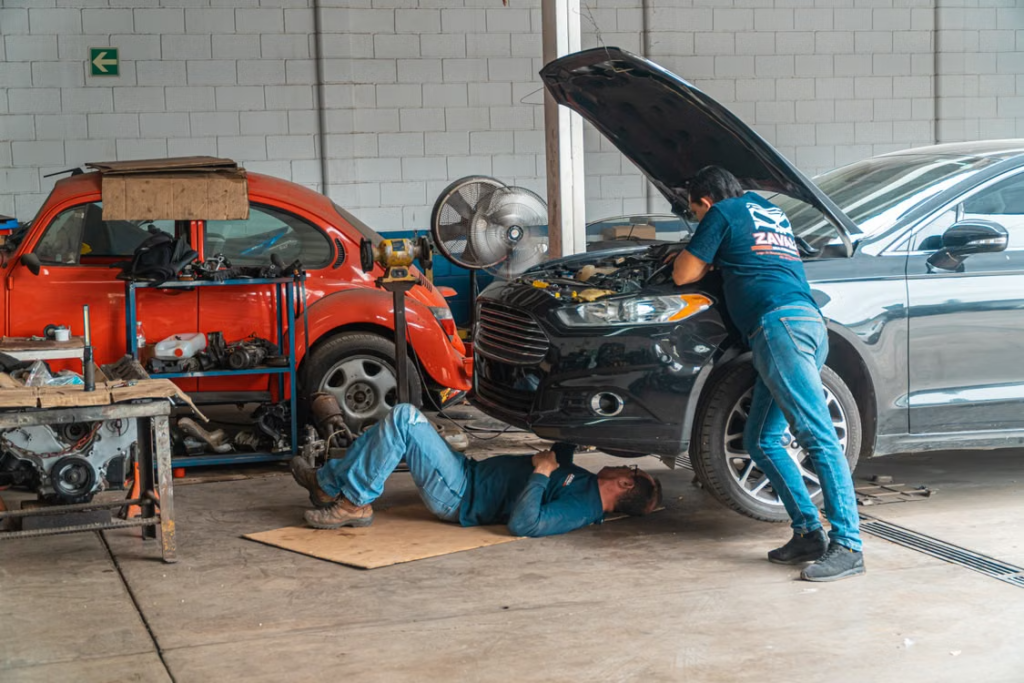 Car maintenance charges: technicians repairing car underneath.