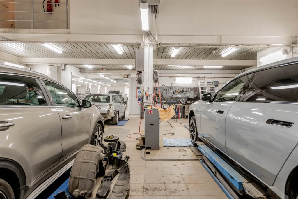 Car maintenance service: vehicles inside repair workshop.